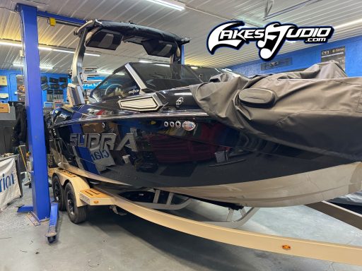 Supra SL550 Boat Black and blue ski boat on a trailer, inside a garage with tools and equipment visible.