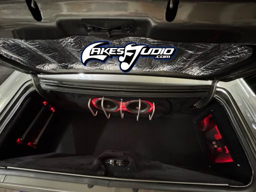 Plymouth Barracuda 'Cuda custom install Car trunk with custom audio setup, illuminated with red lights and featuring a brand logo.