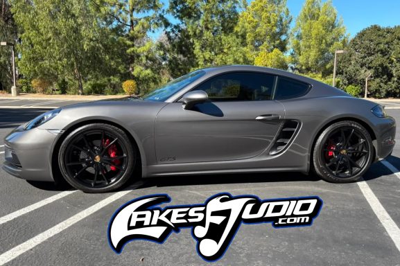 Porsche Side view of a sleek gray sports car parked on a sunny day.