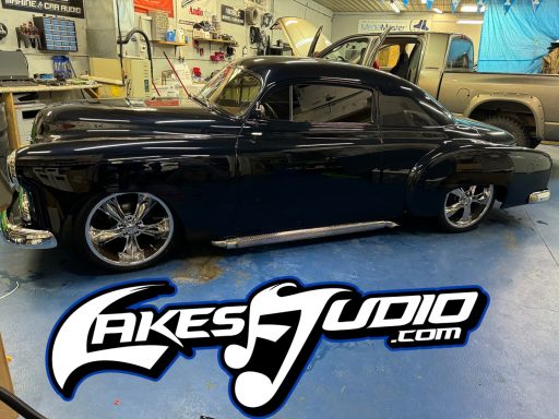 Street Rod A classic black car with custom wheels, displayed in a garage setting.