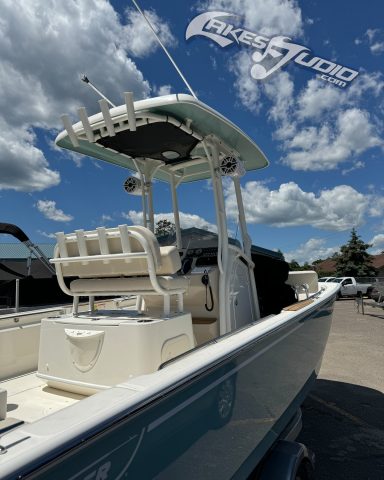Boston Whaler A light blue boat docked, featuring a T-top and seating at the helm, under a cloudy sky.
